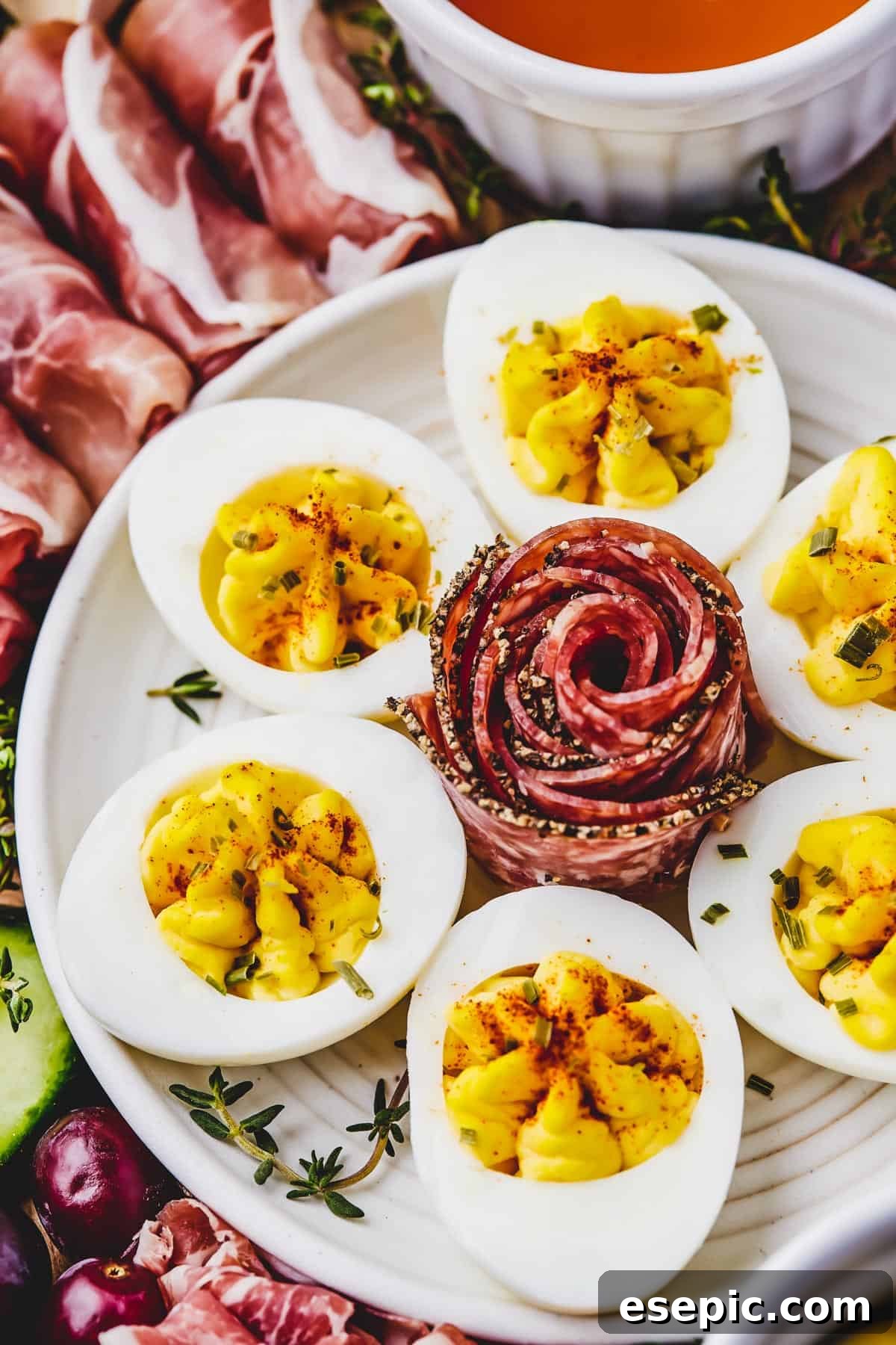 Close-up shot of a plate of deviled eggs with an artistically folded slice of coppa in the center.