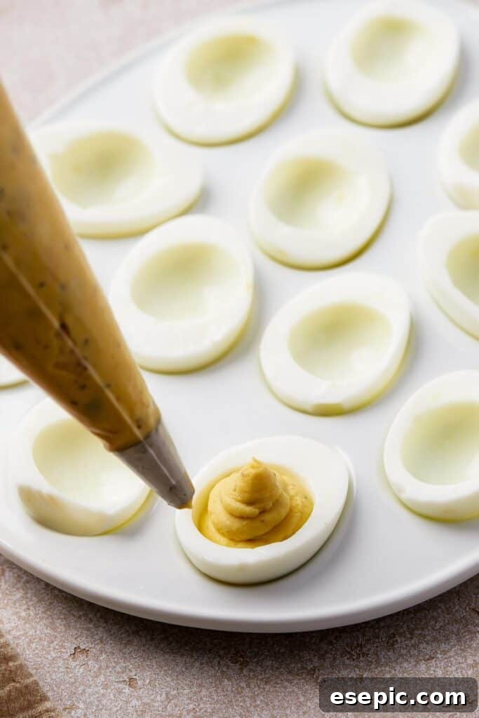 Creamy, yellow filling being piped into hard-boiled egg whites.