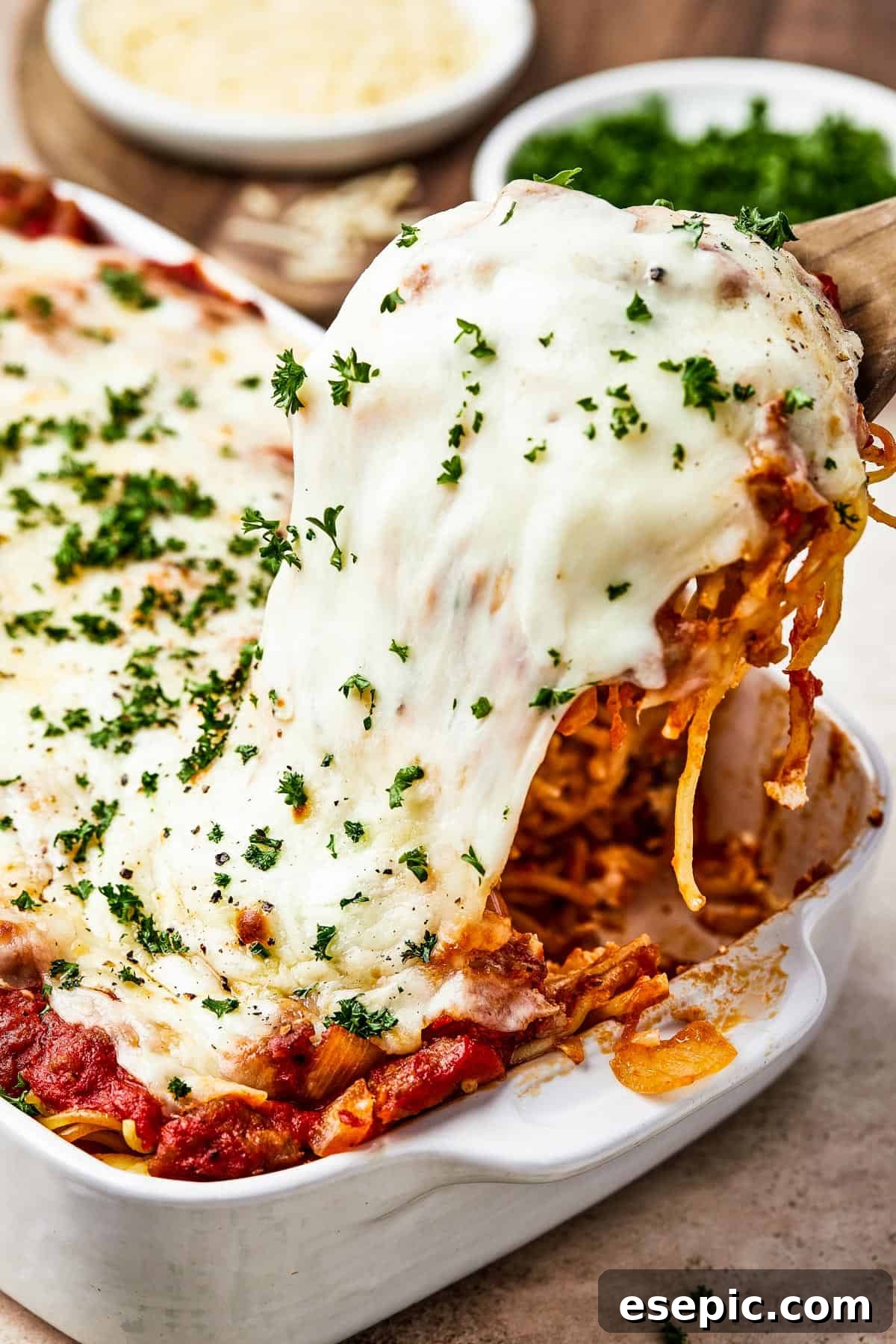 Irresistible Golden Spaghetti Bake 2 A generous portion of baked spaghetti casserole is lifted from a baking dish, revealing the melted, stretchy cheese and rich sauce.