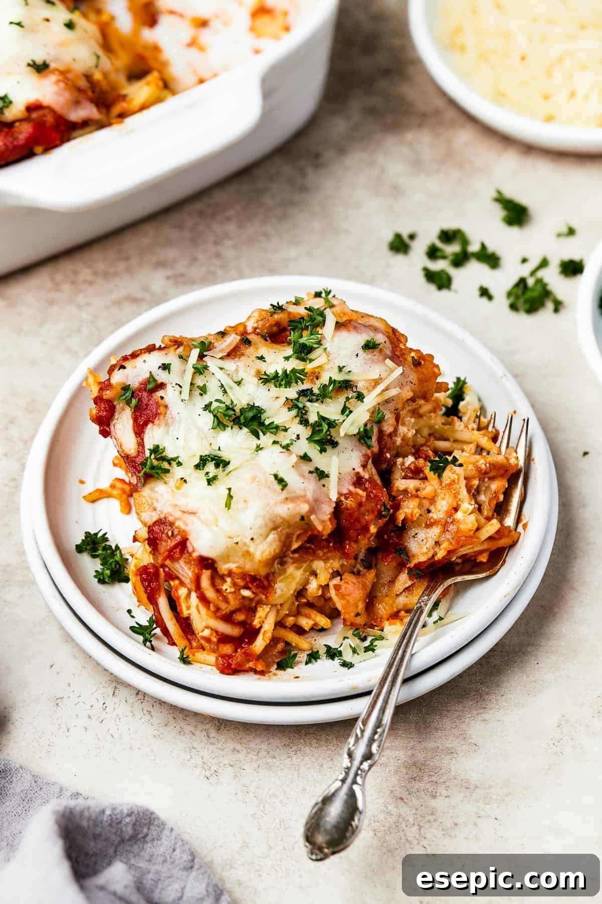 Irresistible Golden Spaghetti Bake 11 A serving of baked spaghetti casserole on a plate, garnished with fresh parsley, ready to be enjoyed.