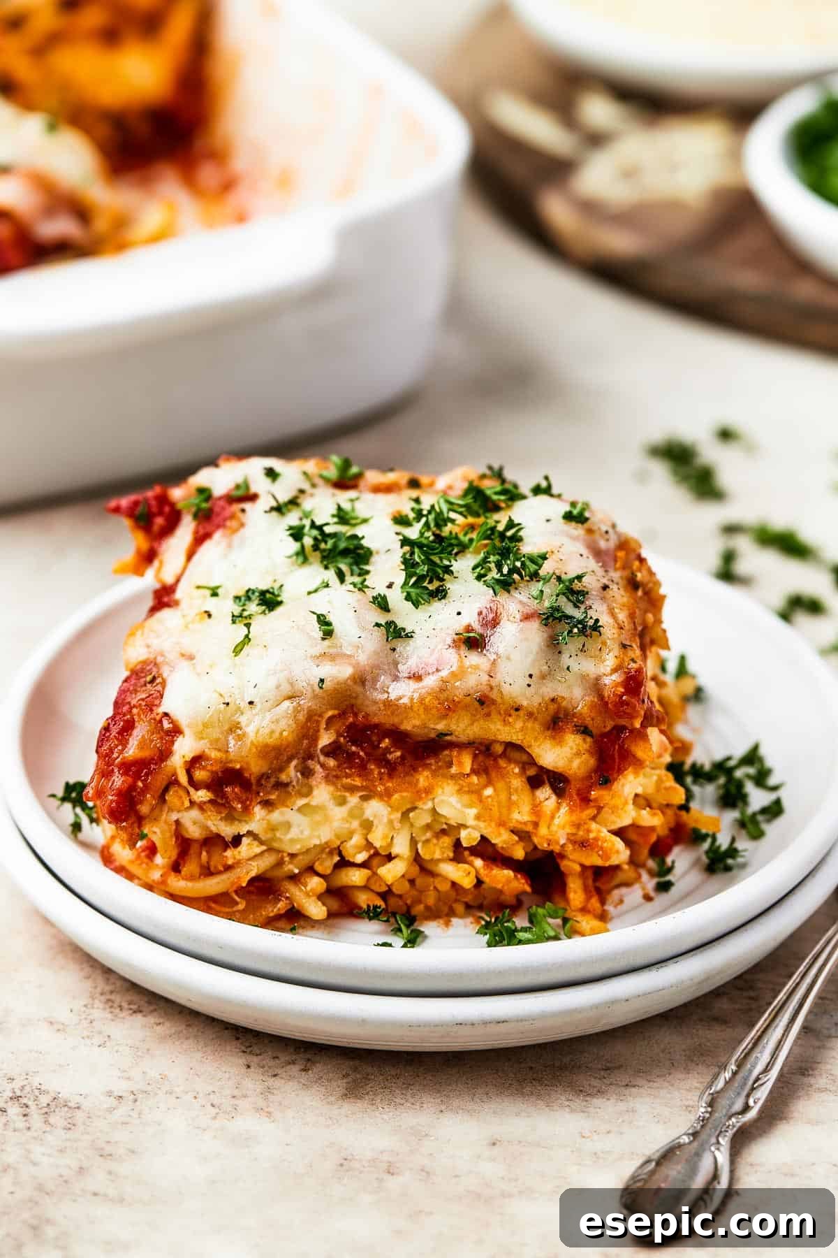 Irresistible Golden Spaghetti Bake 3 A neatly cut square of baked spaghetti, showing the distinct layers, served on a white plate.