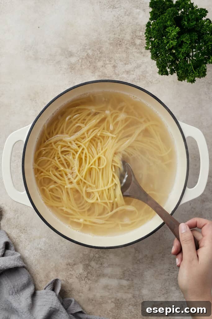 Irresistible Golden Spaghetti Bake 5 Long strands of spaghetti boiling in a large Dutch oven filled with water.