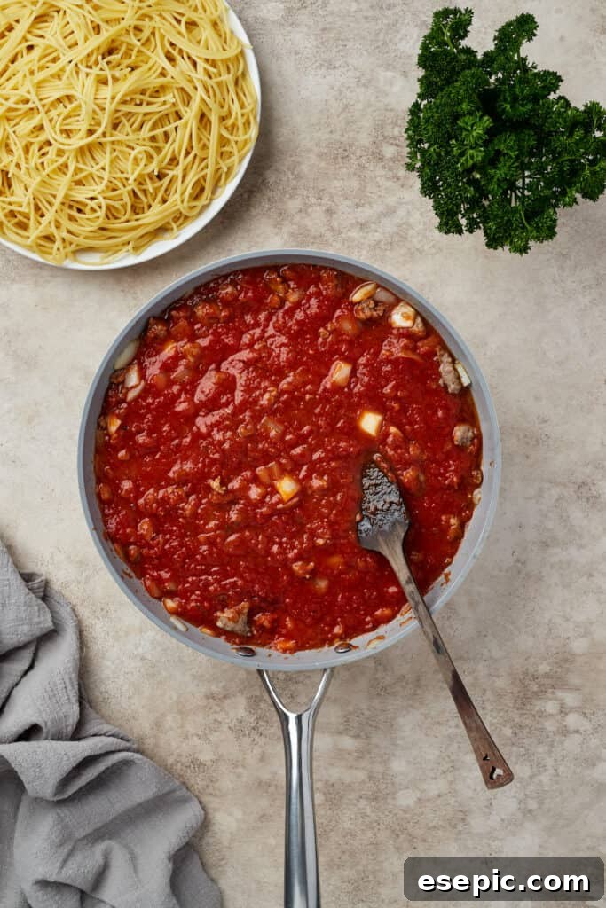 Irresistible Golden Spaghetti Bake 7 A rich meat sauce, made with Italian sausage, simmering in a skillet.