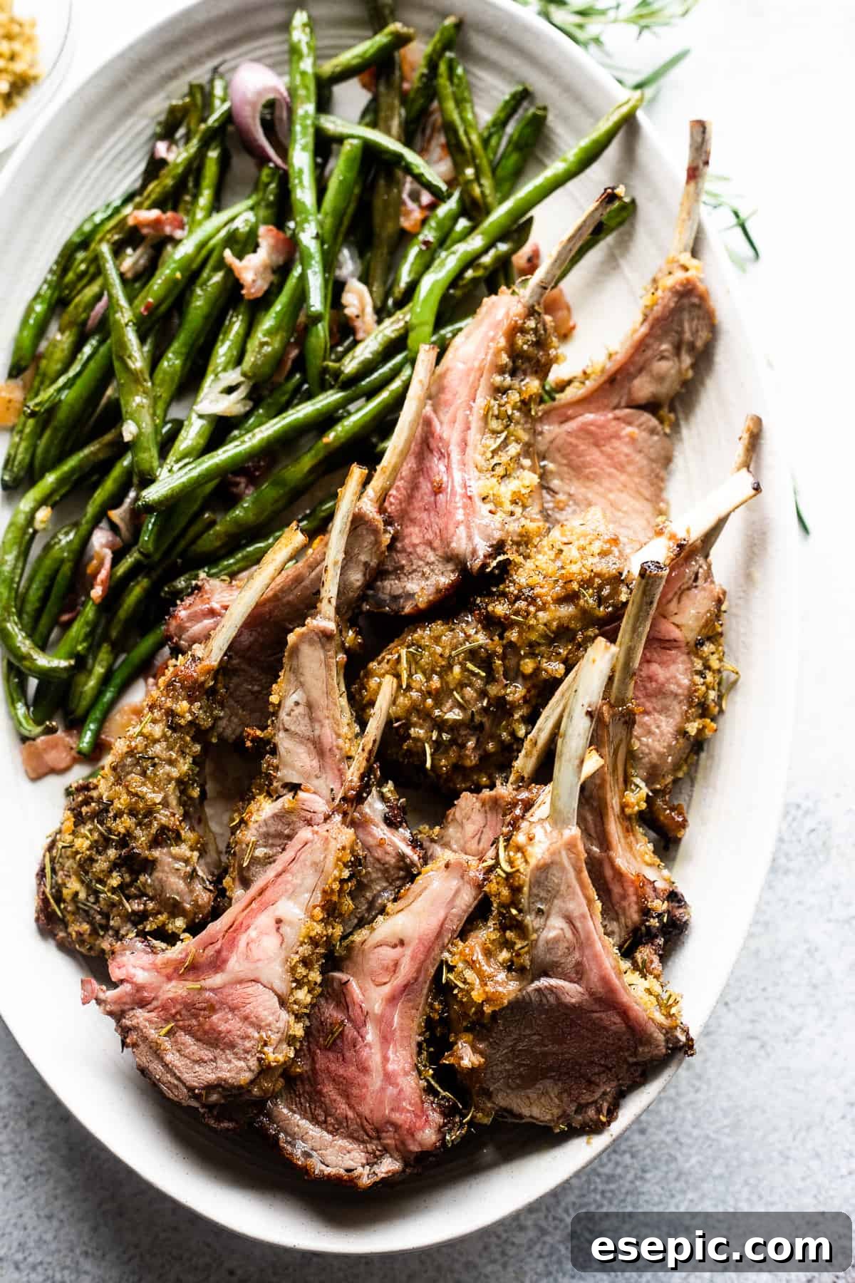 The Definitive Rack of Lamb 2 overhead shot of breadcrumb coated lamb chops arranged on a serving platter with a side of green beans placed above the chops.