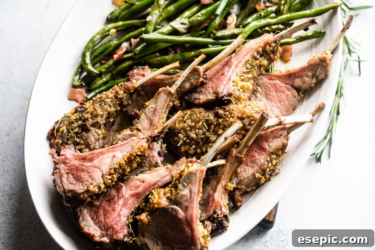 The Definitive Rack of Lamb 6 up close side shot of breadcrumb coated lamb chops arranged on a serving platter with a side of green beans placed above the chops.