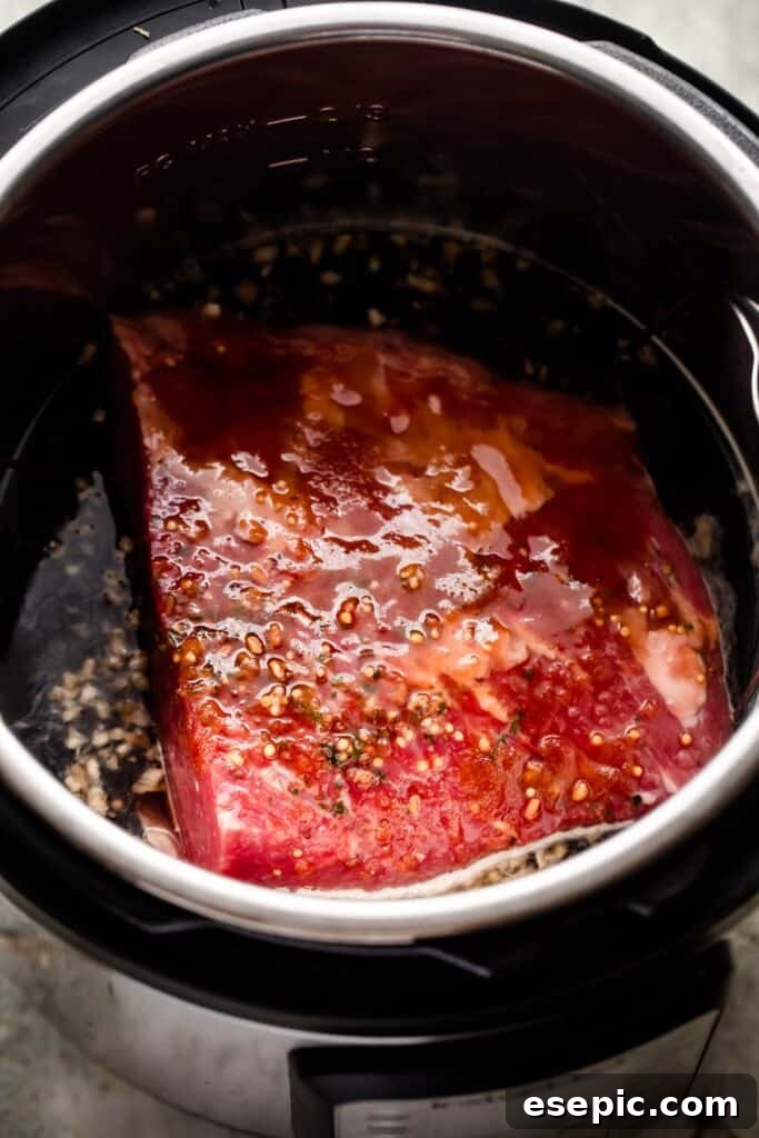 A raw corned beef brisket, seasoned and ready, placed on a trivet inside the Instant Pot before cooking.
