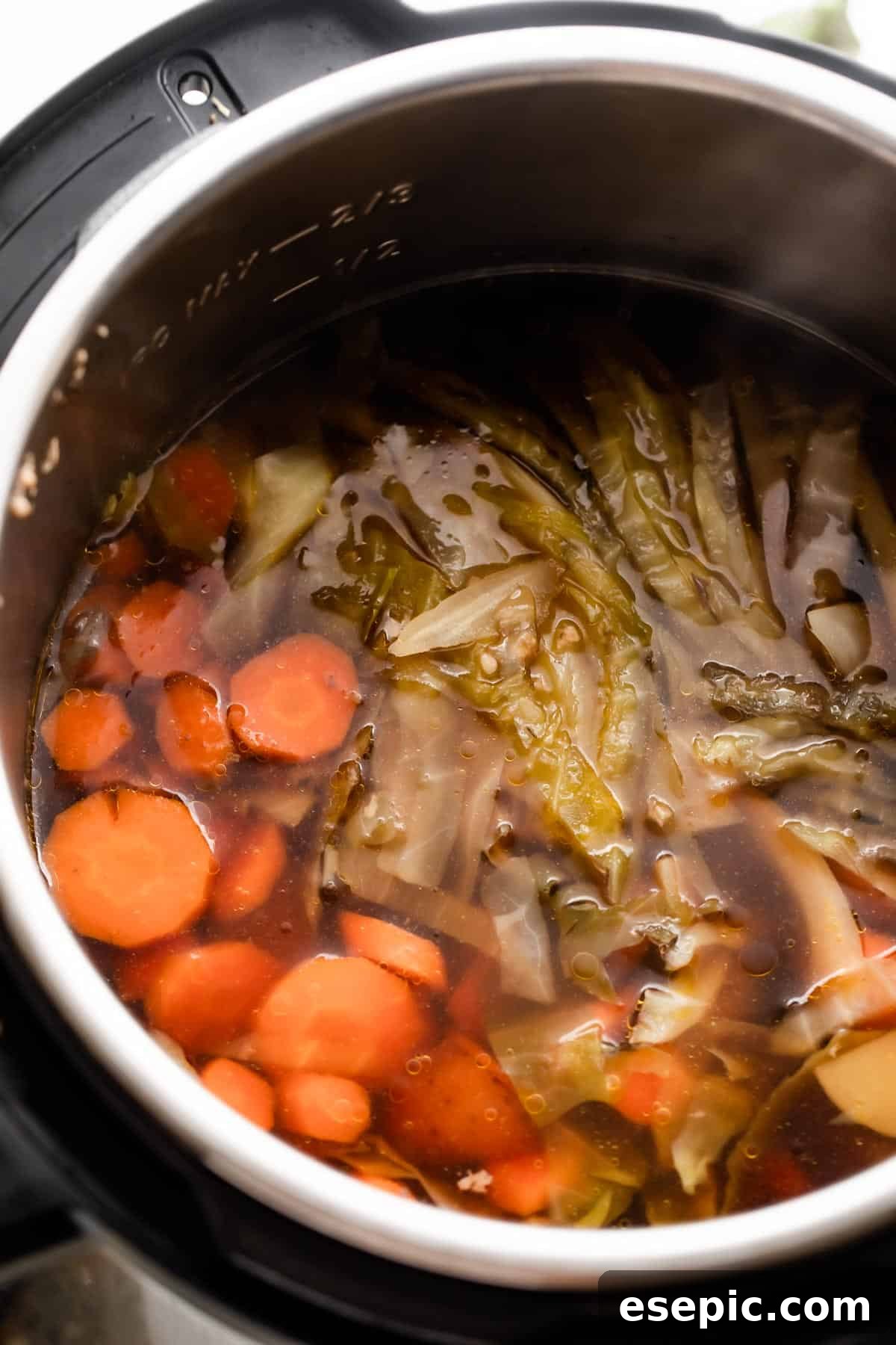 An overhead shot of the Instant Pot insert filled with vibrant, cooked vegetables including sliced carrots, quartered potatoes, and tender cabbage, ready to be served.