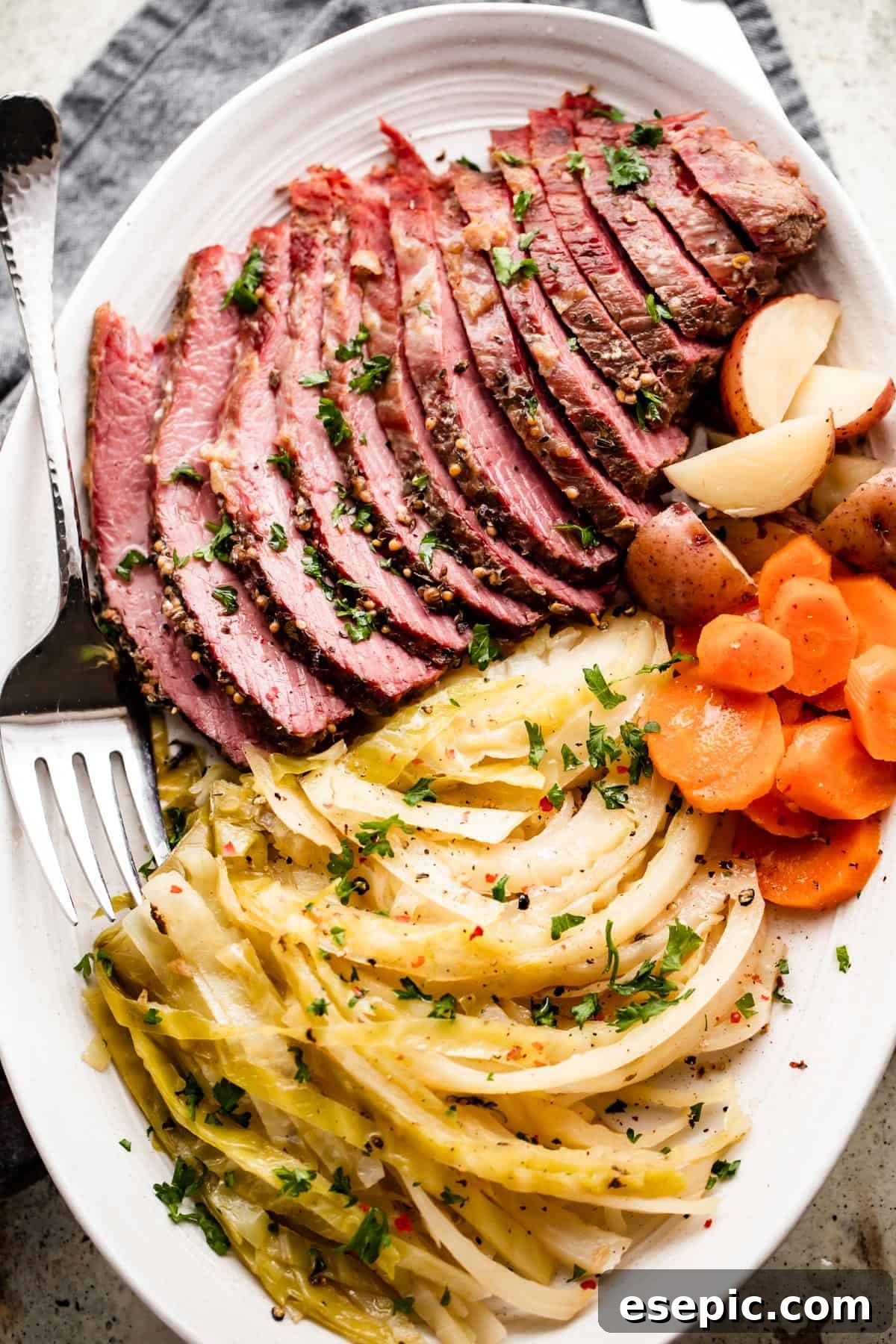 A perfectly arranged oval serving platter featuring tender sliced Instant Pot corned beef, alongside perfectly cooked cabbage, carrots, and potatoes.