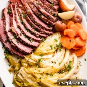 Sliced Instant Pot Corned Beef, cabbage, carrots, and potatoes arranged on an oval serving platter.