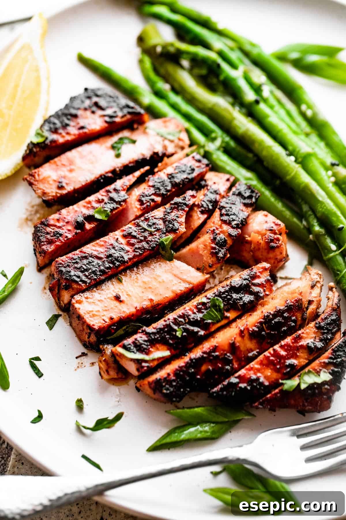 Overhead close-up shot of sliced tuna served on a dinner plate with asparagus stalks.
