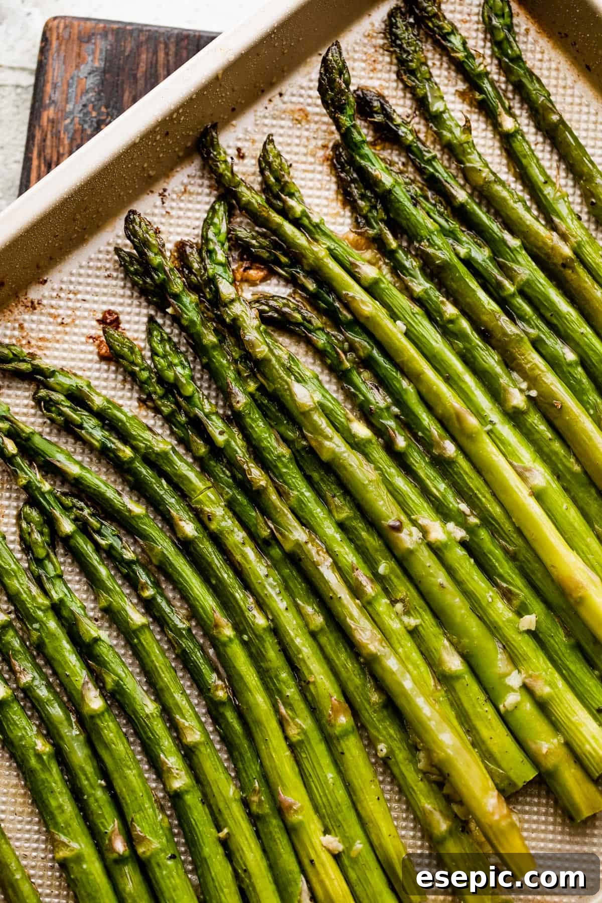 Perfect Garlic Butter Asparagus 2 Crisp asparagus spears beautifully arranged on a golden-colored baking sheet, ready for roasting.