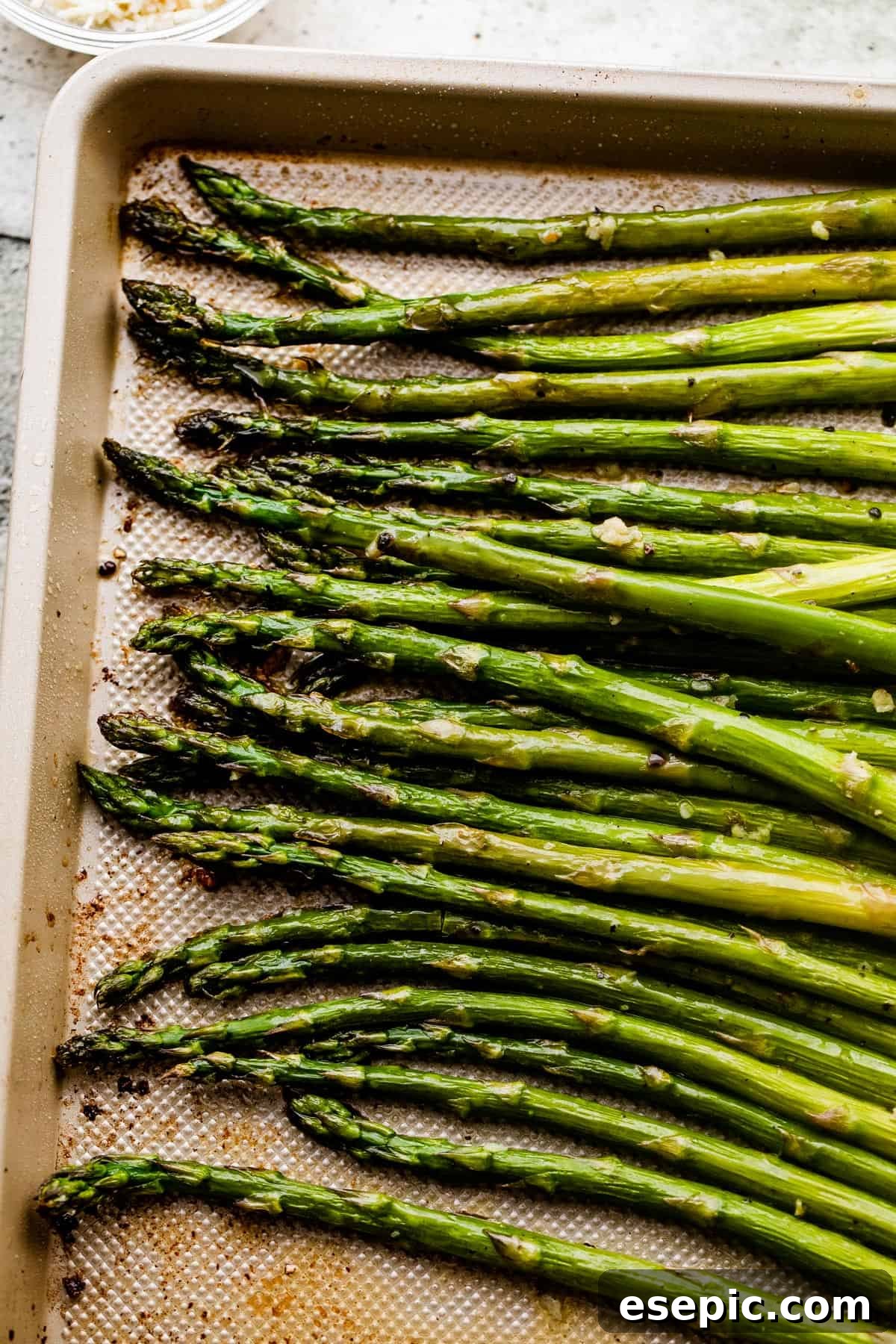 Perfect Garlic Butter Asparagus 3 Overhead shot of perfectly roasted asparagus spears on a baking sheet, glistening with garlic butter.