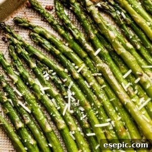 Parmesan-topped asparagus spears arranged on a gold-colored baking sheet, ready to be served.
