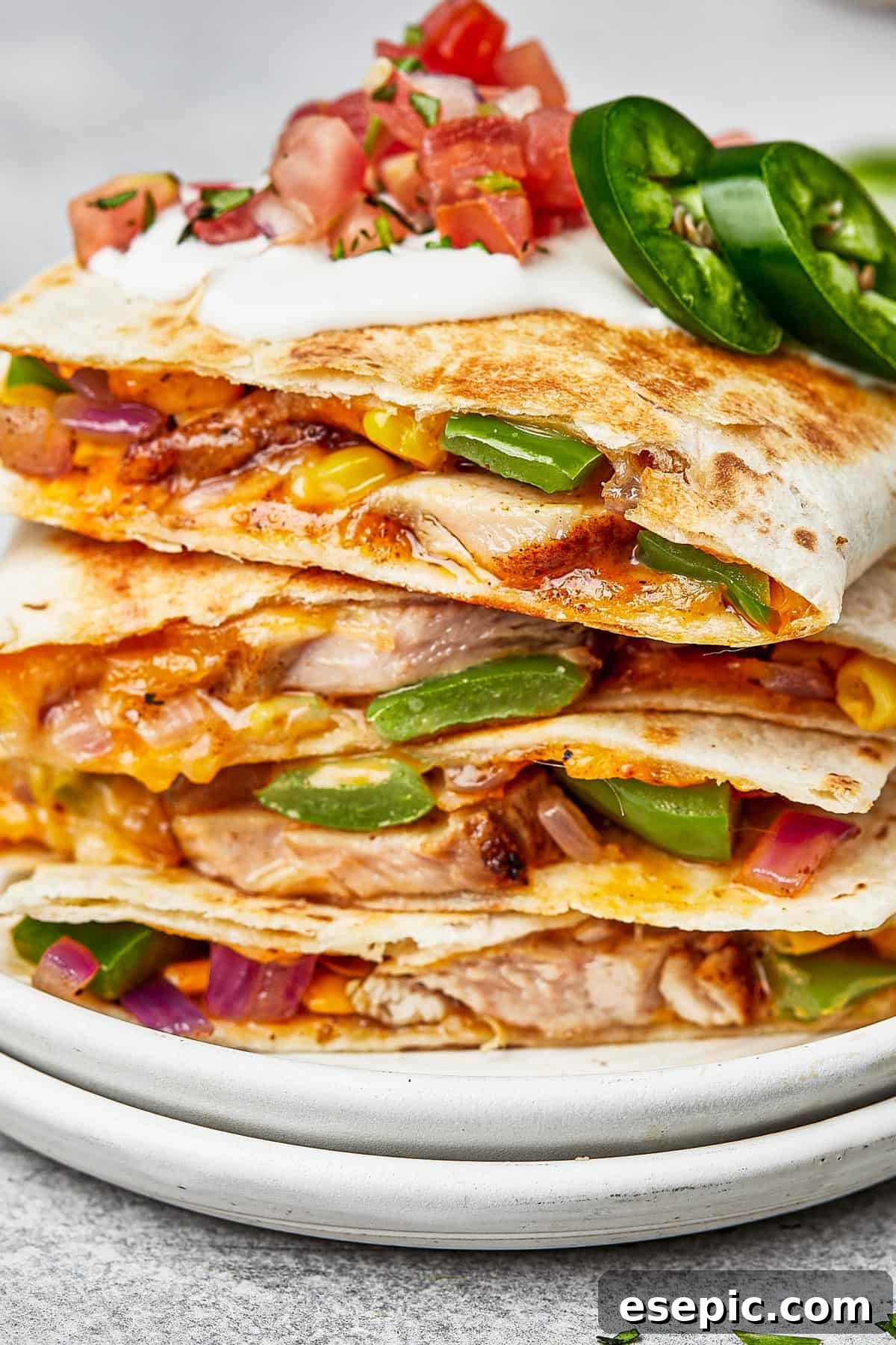 Chicken quesadillas stacked on a plate, viewed from the side to show texture and golden brown tortillas.