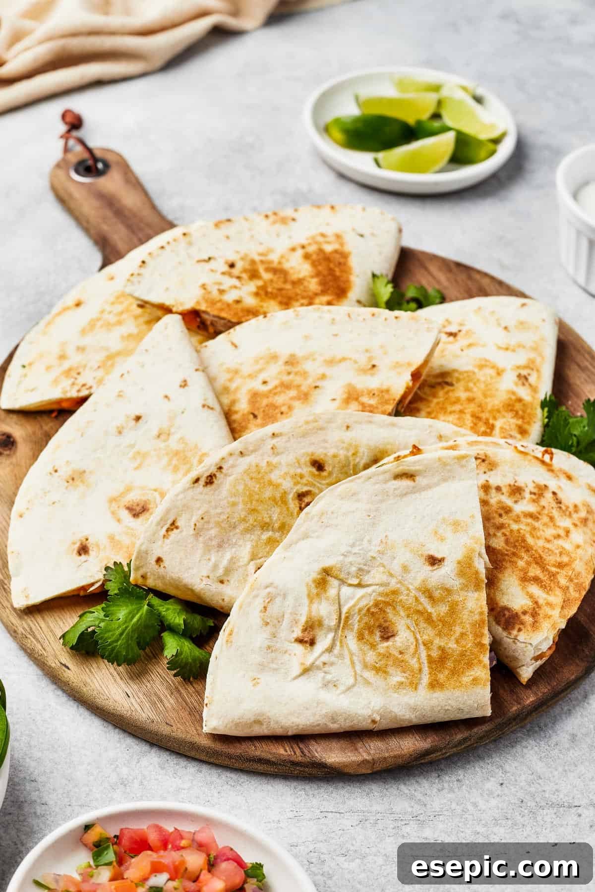 Crispy chicken quesadilla wedges fanned out on a rustic wooden board, garnished with fresh jalapeno slices.