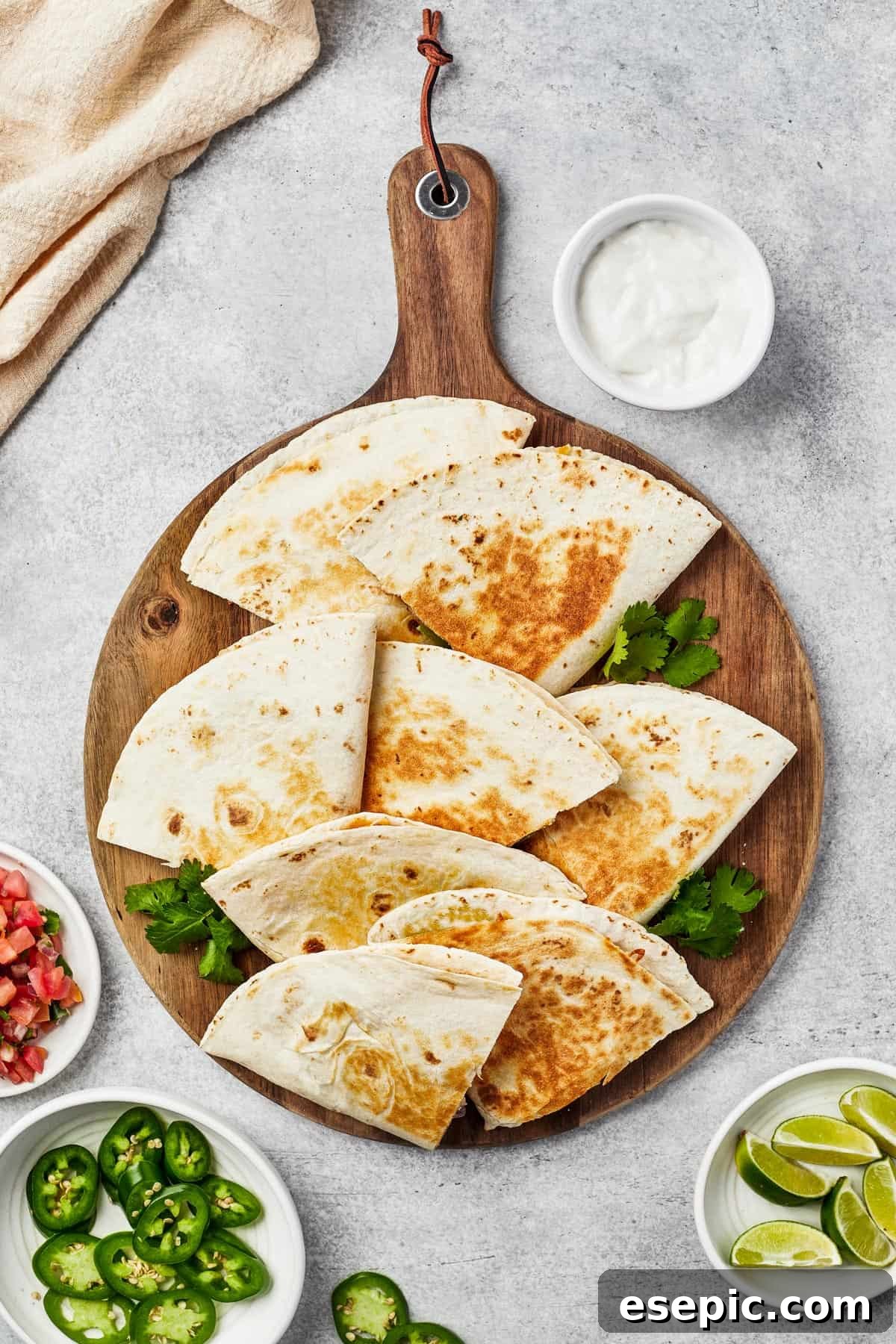Perfectly cooked tortilla wedges fanned out on a wooden board, garnished with fresh jalapeno slices, ready to be served.