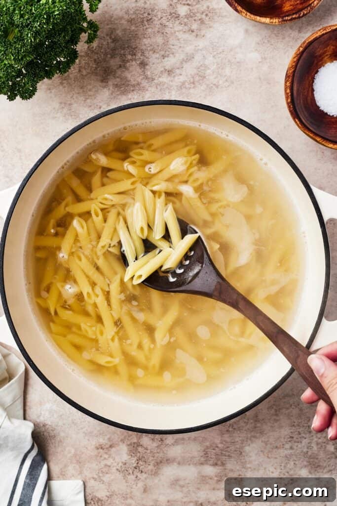 Pasta boiling in a large pot on the stovetop, surrounded by steam.