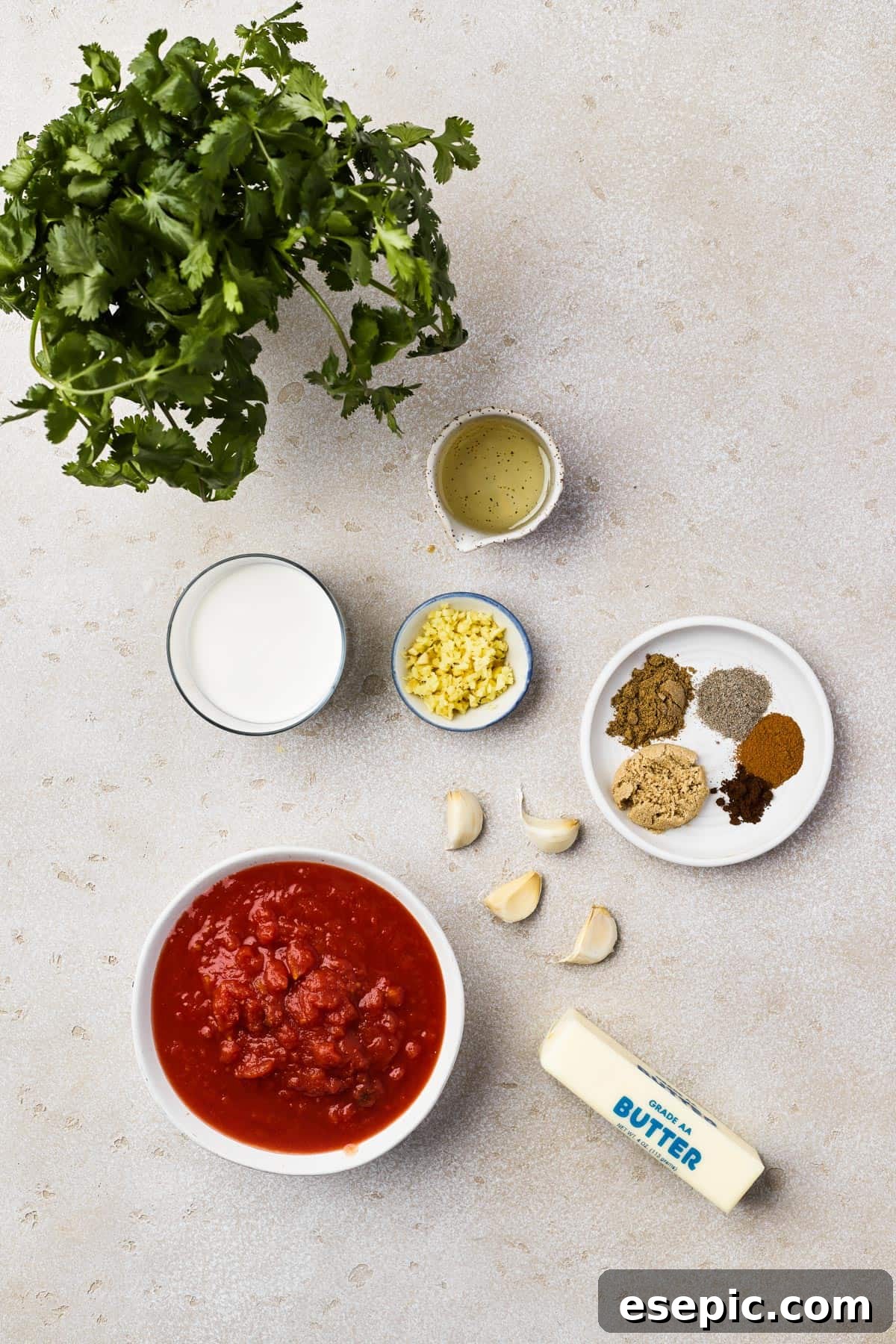 A vibrant display of fresh cilantro, vegetable oil, heavy cream, minced ginger, a variety of aromatic spices, garlic, crushed tomatoes, and rich butter – all the essential ingredients for a delicious Butter Chicken.
