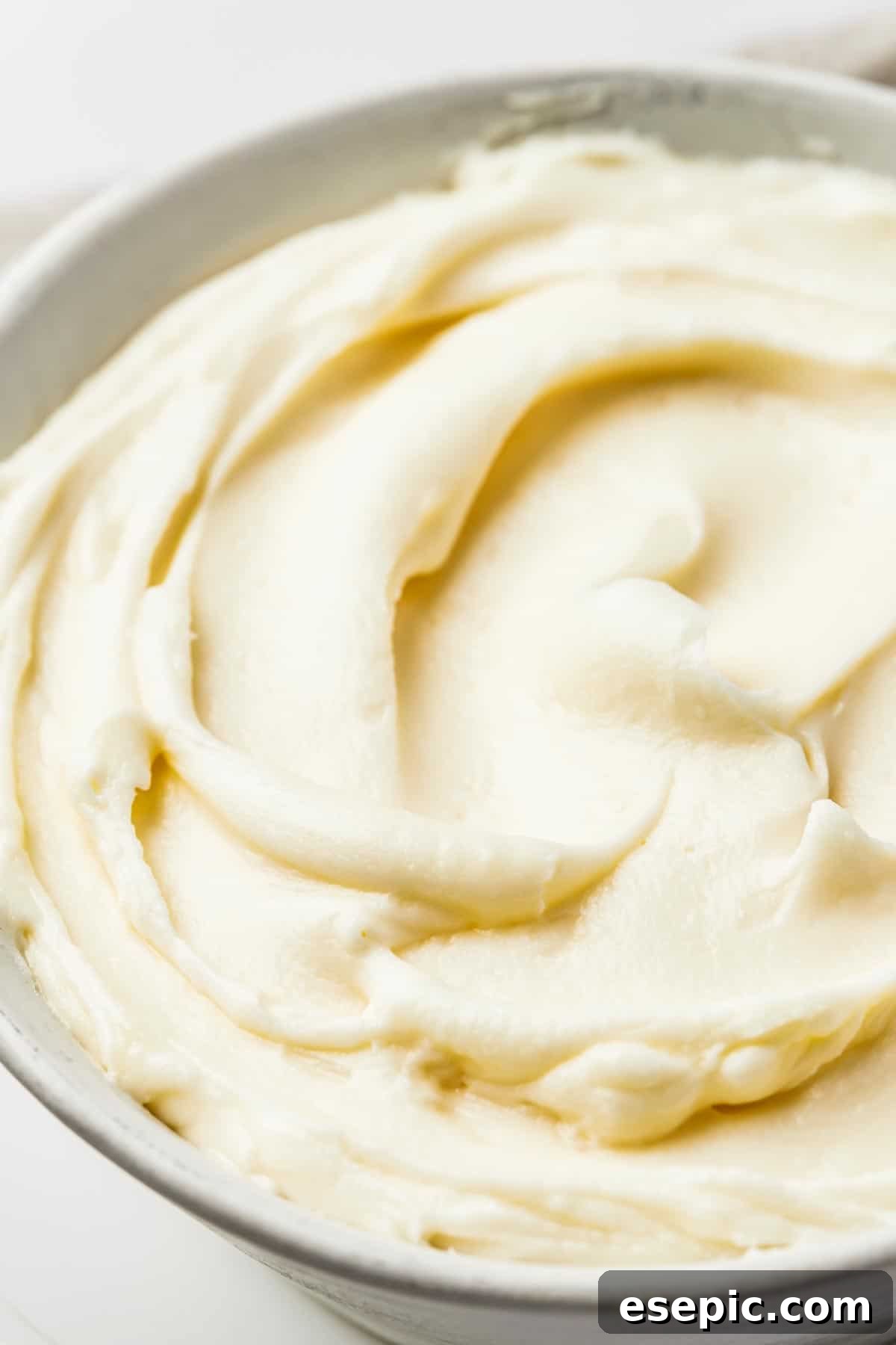 The Ultimate Cream Cheese Frosting 3 Close-up shot of white cream cheese frosting, swirled in a large mixing bowl.
