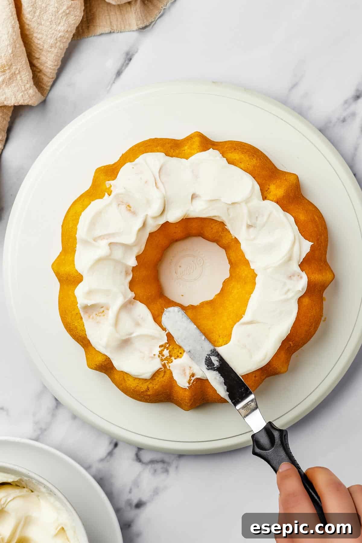 The Ultimate Cream Cheese Frosting 7 Overhead shot of a bundt cake generously iced with thick, creamy cream cheese frosting, ready for serving.