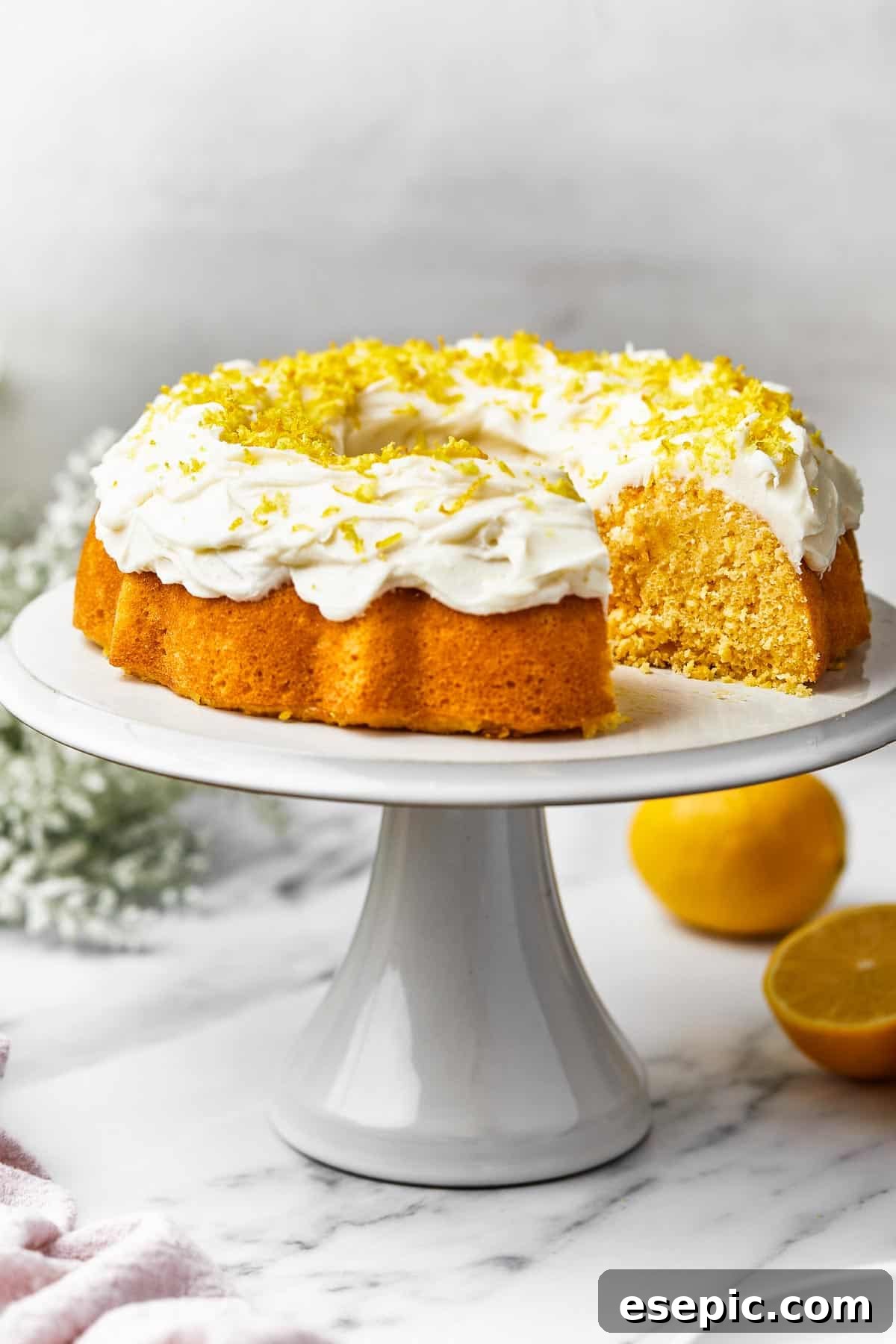 A freshly baked lemon Bundt cake resting on an elegant platter, with one perfect slice carefully removed, revealing its tender, golden crumb.