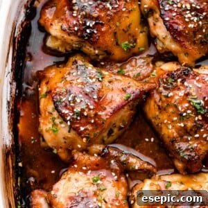 overhead shot of a baking dish with six honey garlic baked chicken thighs garnished with sesame seeds.