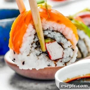 A bite of sushi held in a pair of chopsticks. A small plate of sushi and a container of soy sauce is in the background.