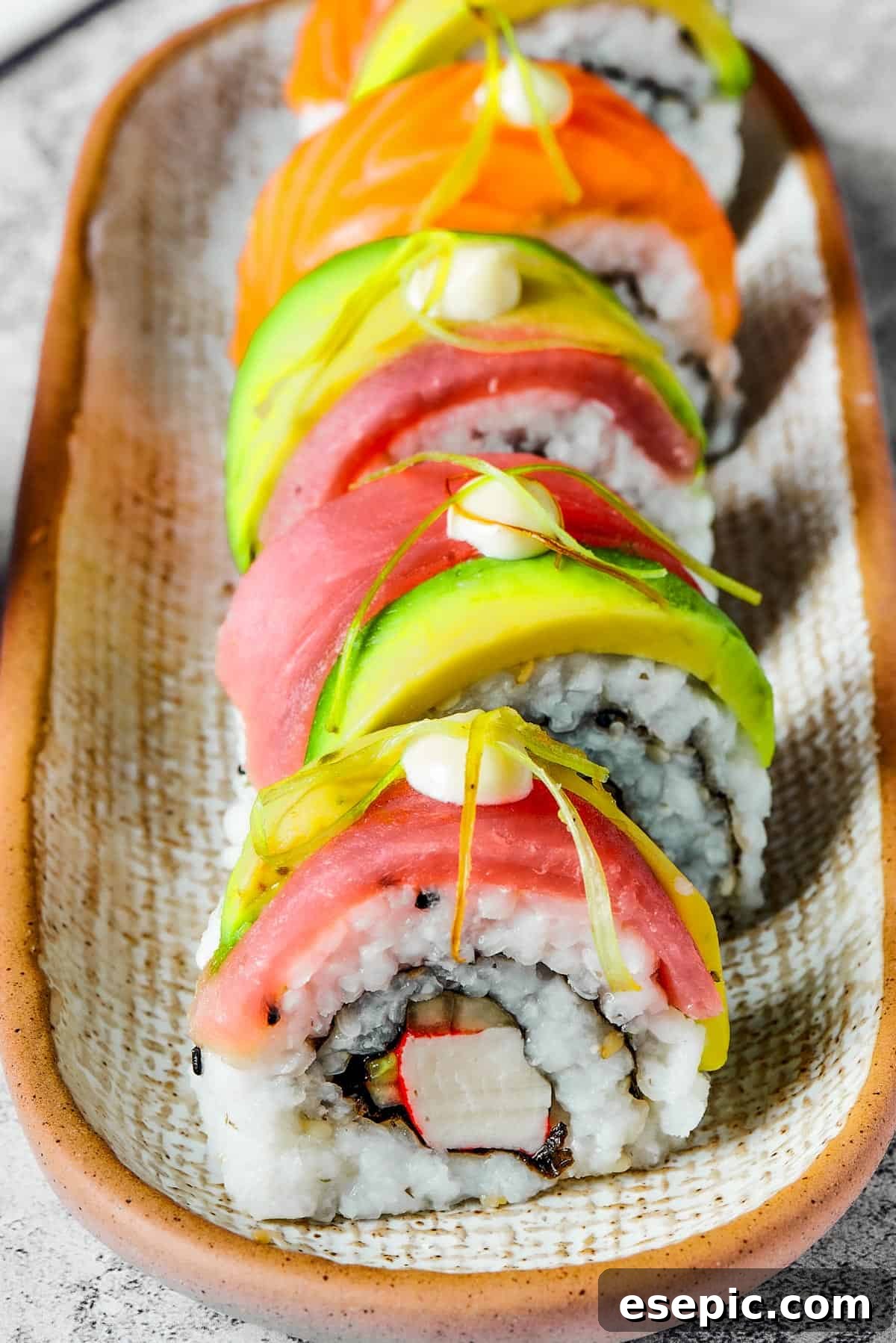 A narrow plate with five pieces of sushi lined up on it.