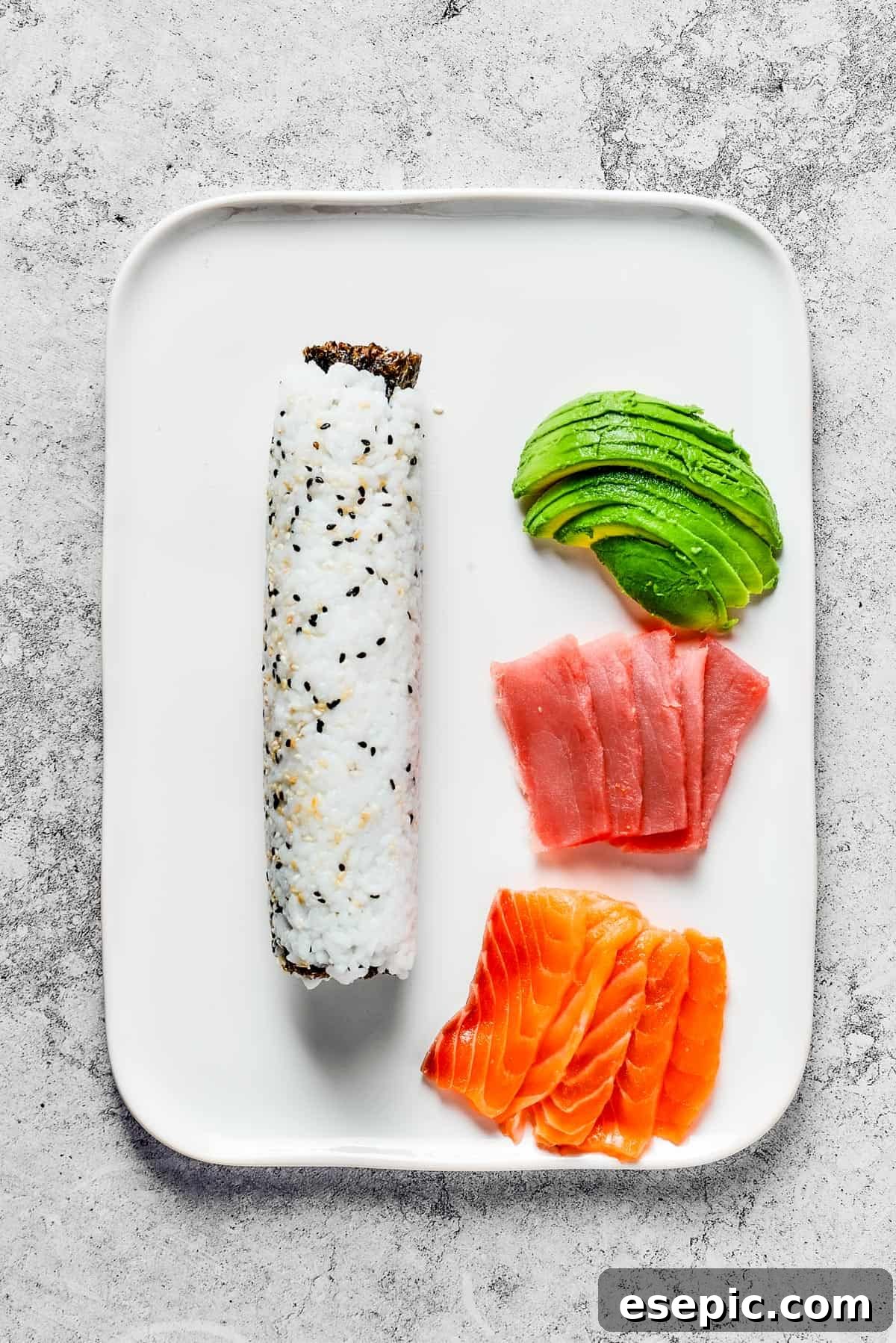 A platter with rolled sushi and toppings of avocado, tuna, and salmon.