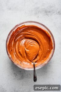 A smooth blend of melted peanut butter, chocolate, butter, vanilla, and sea salt in a glass mixing bowl.
