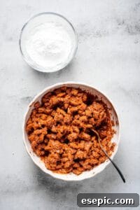 Chex cereal coated in chocolate and peanut butter, with a bowl of powdered sugar nearby.
