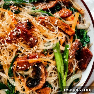 overhead shot of a shallow dish of beef noodle stir fry, garnished with sesame seeds.