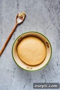 A smooth, perfectly formed ball of dough resting in a large ceramic bowl, ready for its first rise.