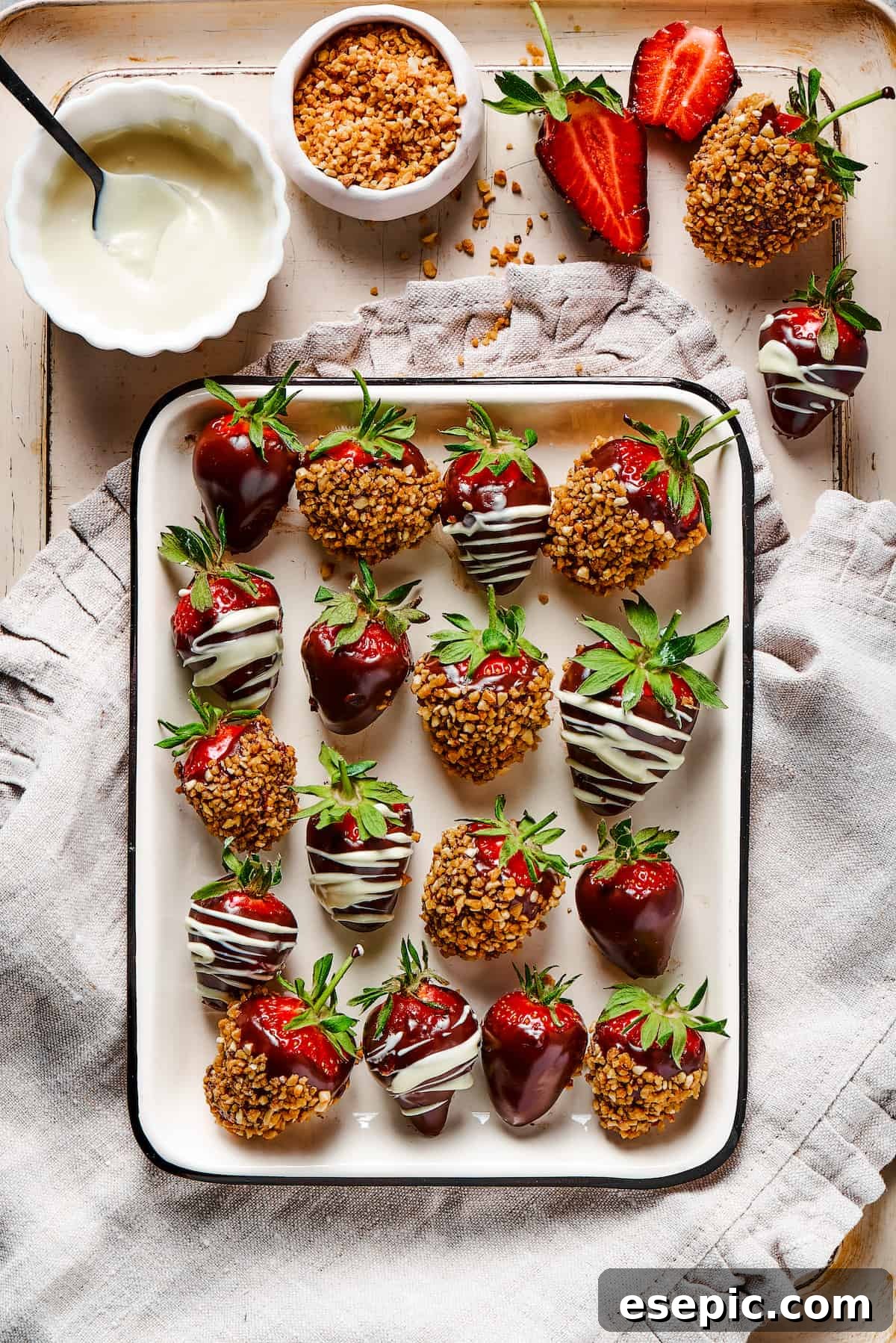 Effortless Chocolate Strawberry Delight 8 Beautifully arranged chocolate-covered strawberries resting on a decorative tray, placed on a striped dishtowel next to a small bowl of white chocolate, ready for finishing touches.