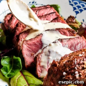 Steak slices with creamy sauce being spooned over the top.