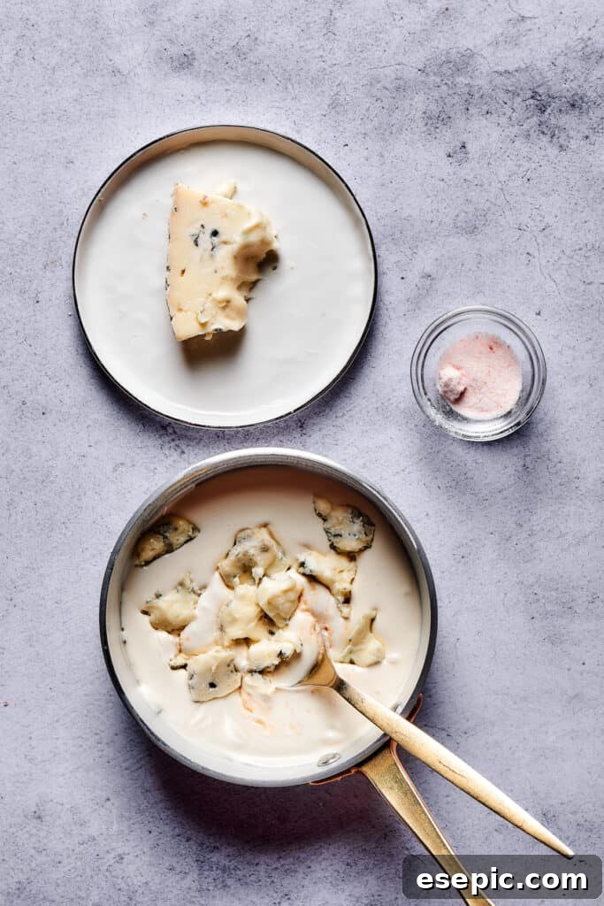 Chunks of piquant blue cheese slowly melting and being stirred into a saucepan of luscious, creamy sauce.