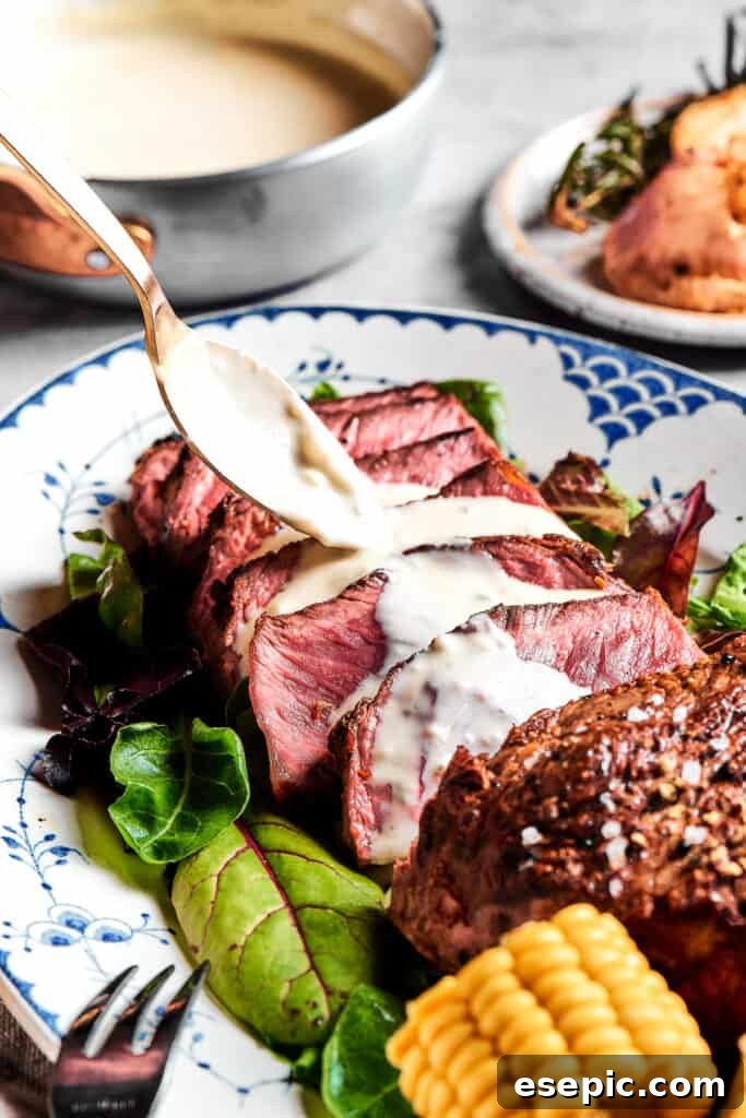 Blue Steak Explained: Should You Eat It 5 Exquisitely sliced blue steak arranged on a serving plate, with a generous spoonful of creamy blue cheese sauce being drizzled over the top.