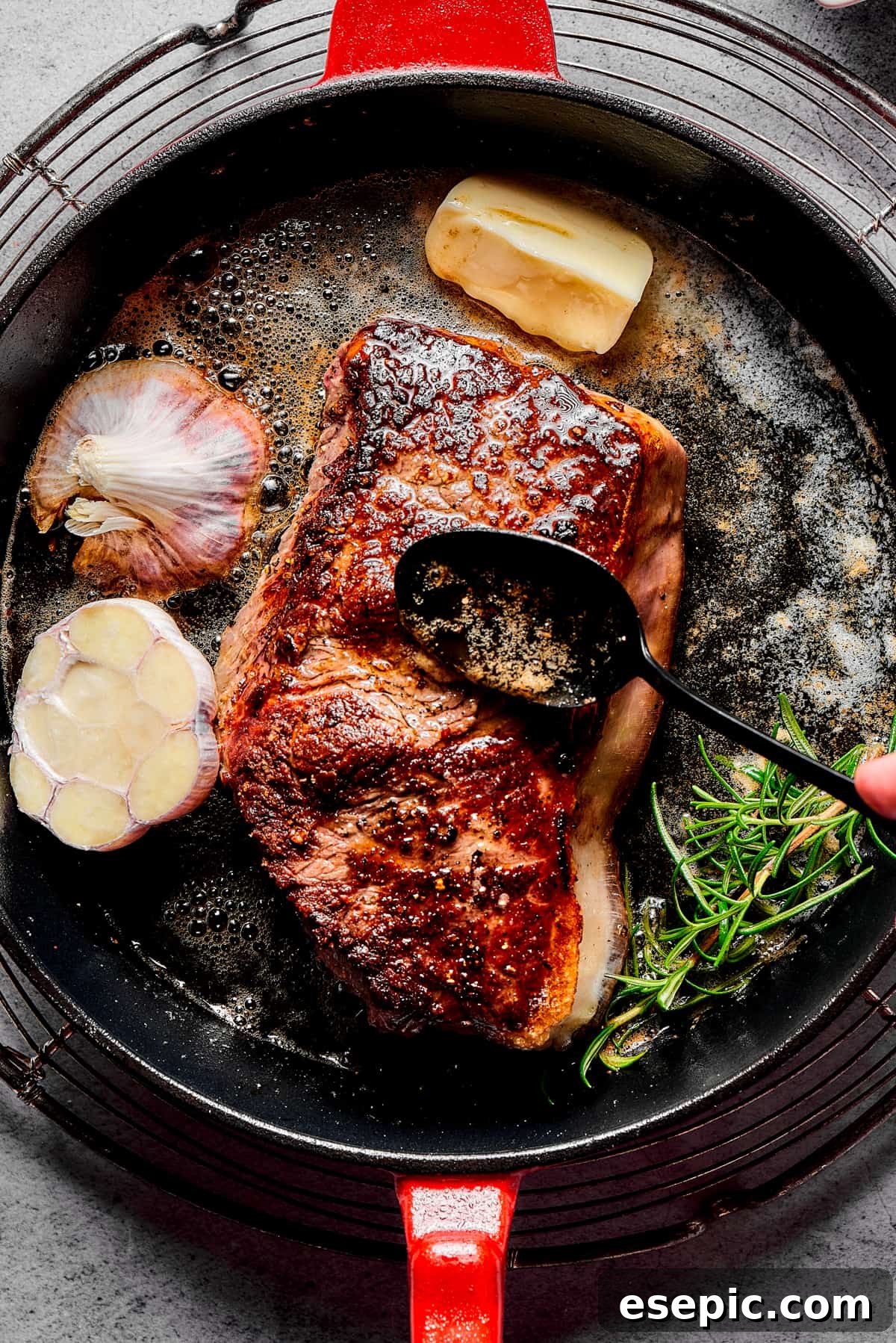 The Art of Basting: Infusing Flavor into Your Blue Steak A chef's hand skillfully basting a sizzling steak with aromatic pan juices, butter, and herbs as it cooks in a hot cast-iron skillet.
