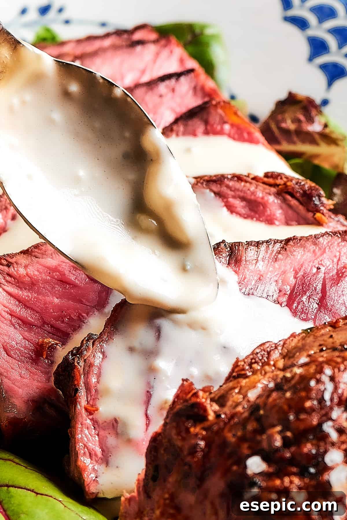 Artfully sliced blue steak, glistening with creamy sauce delicately spooned over its rare, tender segments.