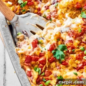 A serving utensil in a large baking pan of cheesy chicken bake.