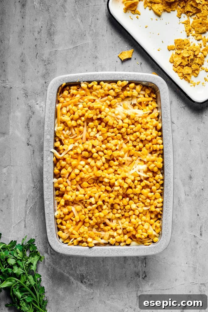 A baking pan with layers of ingredients inside. Corn is the top layer.