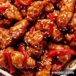 Overhead shot of saucy chicken pieces, garnished with sesame seeds.