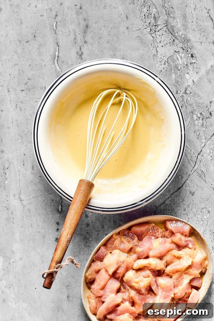 A bowl of batter and a bowl of cut up chicken breast.