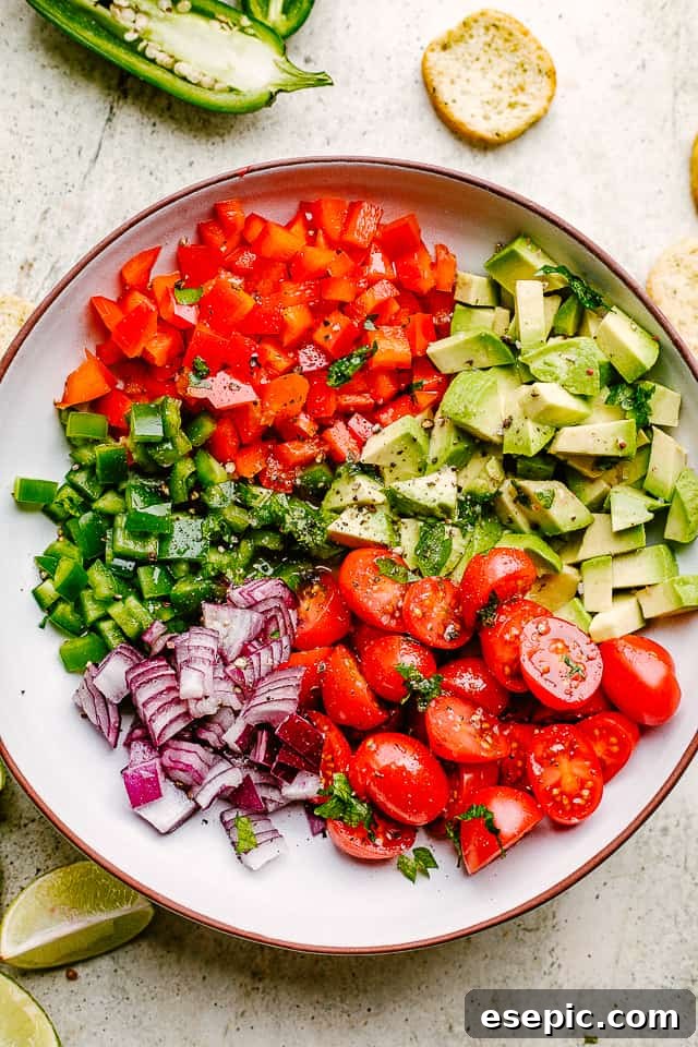 Close-up of freshly diced vegetables, including peppers, red onions, tomatoes, and avocado, ready to be combined for a delicious salsa.