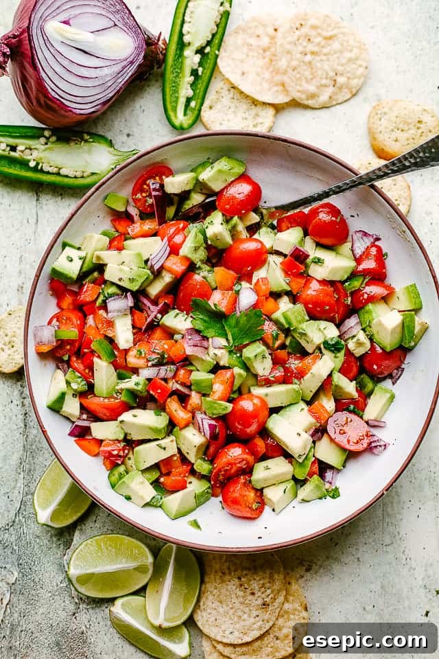 A bowl of homemade avocado salsa with a generous pile of tortilla chips on the side, ready for dipping.