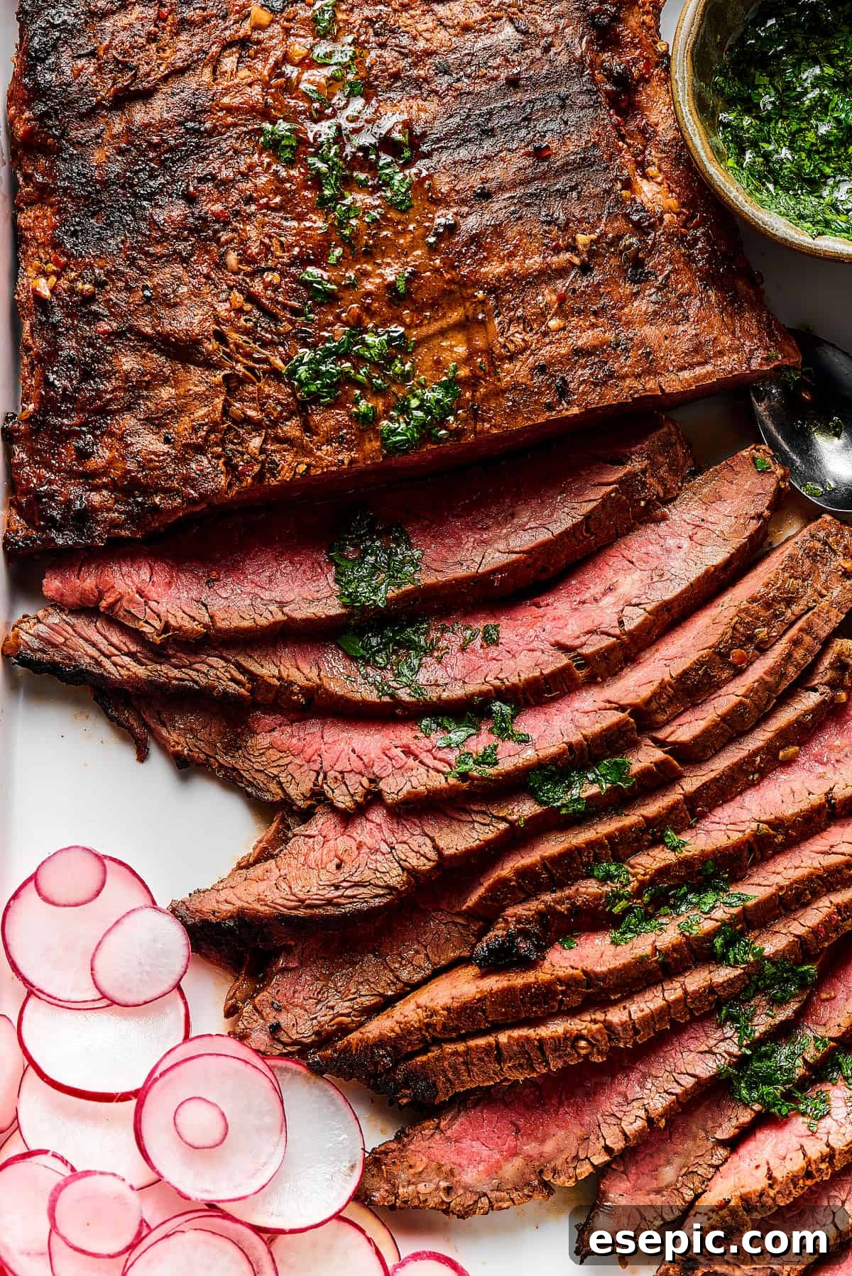 Orange and lime juice, garlic and jalapeno, maple and cumin - this easy Grilled Carne Asada is drenched in a medley of mouthwatering flavors! Thinly sliced grilled carne asada on a serving platter, garnished with fresh herbs.