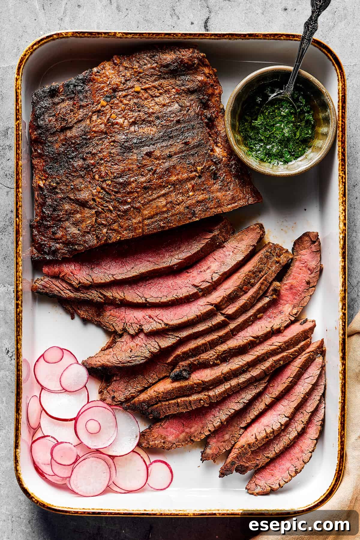 Orange and lime juice, garlic and jalapeno, maple and cumin - this easy Grilled Carne Asada is drenched in a medley of mouthwatering flavors! Grilled flank steak, partially sliced into thin strips, with a cup of dipping sauce on one side and a sliced radish on the other, arranged on a rustic cutting board.