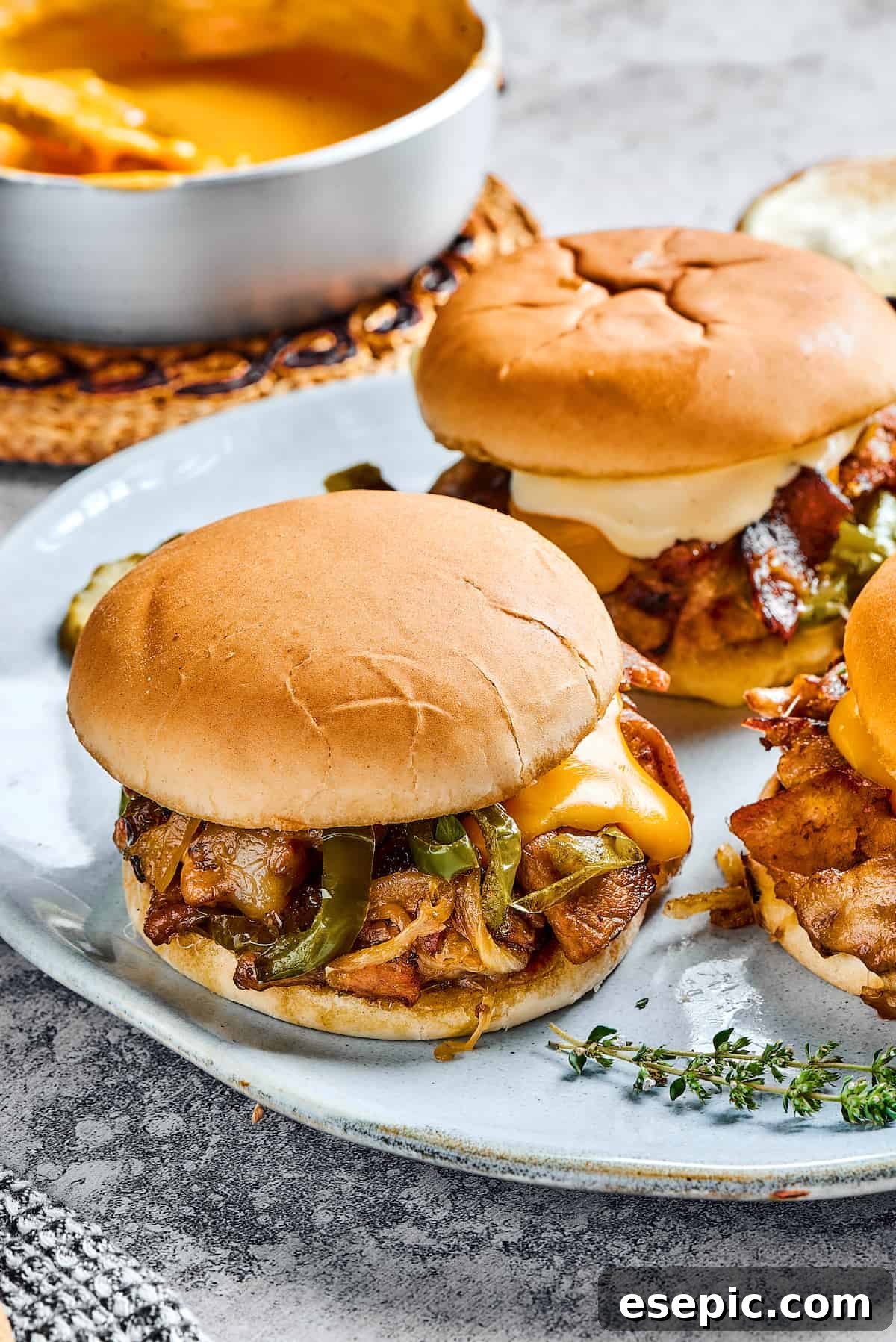 Two steak sandwiches with onions, melted cheese, and bell peppers.