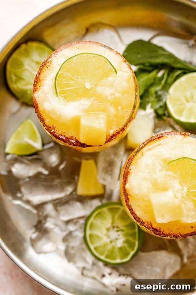 Sun-Kissed Pineapple Margaritas 5 Top view of frozen margaritas garnished with limes and pineapples, showcasing the perfect rim.