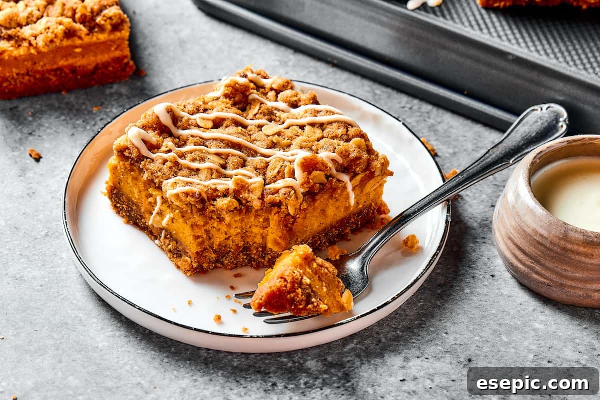 A single pumpkin cheesecake bar served on a small white dessert plate, with a fork ready to enjoy.